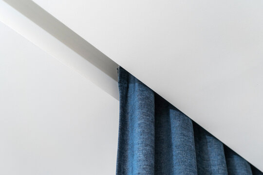 Close up of white ceiling board, curtain rail with blue textile in bedroom