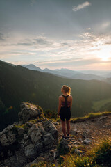 Rear view shot of young fit woman in stylish sportswear looking on the scenic view of mountains on beautiful sunset. Rysy mountains, Tatras. Poland, Slovakia