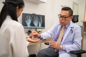 Mature male doctor explain to the woman patient the result of x-ray that show fracture of her calcaneus. Doctor Showing X-ray To Patient On Computer Screen.