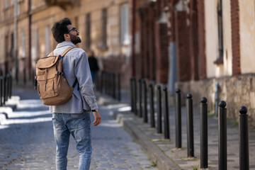 Tall dark-haired tourist in the city street looking interested