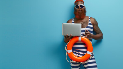 joyful man with red-dyed hair and a full beard, wearing round sunglasses, a striped tank top, holding a laptop in one hand, and an orange lifebuoy