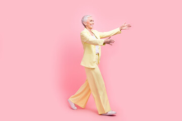 Full body photo of friendly cheerful person dressed yellow jacket stretching arms to empty space isolated on pink color background