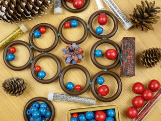 Handmade Christmas tree made of wooden rings and beads on a wooden board, vintage background. Improvised materials for making craft: beads, rings, decorative glitter in powder. Holiday concept