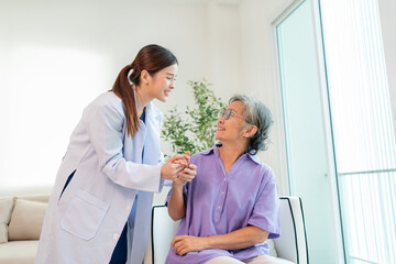 Obraz premium Asian female doctor taking care and talking mature female patient sitting on sofa in hospital. Healthcare concept.