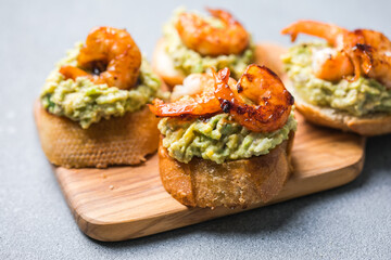 Appetizer canape with shrimp on cutting board on table close up