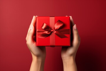 Top view of hands holding craft red paper gift box with ribbon bow on isolated red  background. Generated AI. - obrazy, fototapety, plakaty