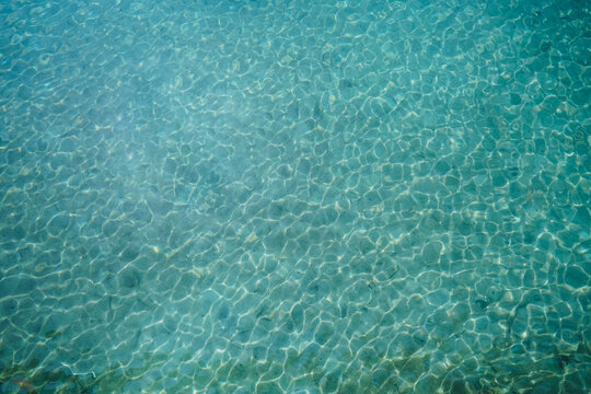 Blue water surface viewed from above in outdoor sea, sun reflection, dimply. Surface Abstract Background. Clear water in sea with ripple in clean aqua liquid. Summer wallpaper blue background