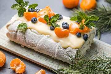 Meringue roll Pavlova cake with cream and fresh orange on top on a gray background. Copy space.
