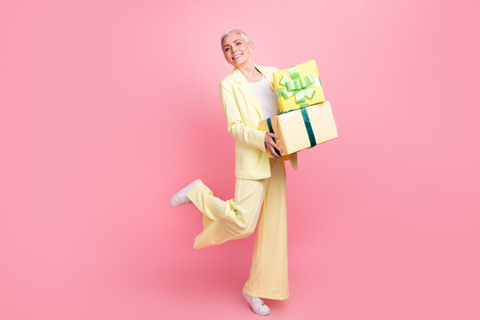 Full length body photo of funky glamour lady with short white hair hold pile gifts she prepared for kids isolated on pink color background