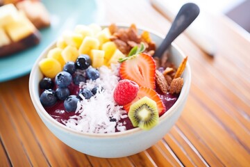 close-up acai bowl with focus on spoon filled with berries
