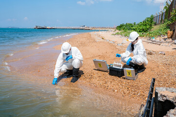 Scientists biologists and researchers in protective suits taking water samples from waste water from industrial. Experts analyze the water in a contaminated environment. 