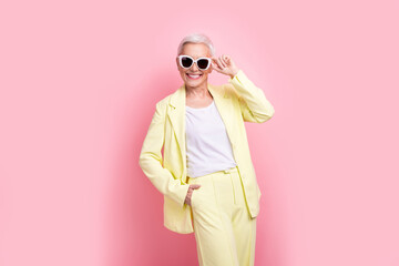 Photo successful rich businesswoman touching sunglasses wear yellow suit posing at fashion week festival isolated on pink color background