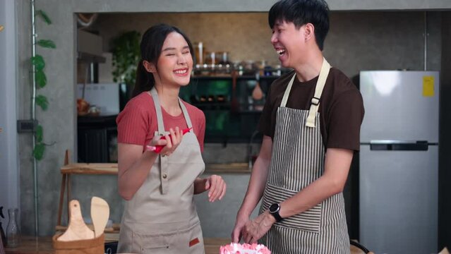 slow motion VDO. Portrait asian couple chef looking at camera. Homemade, happy relaxing and wellness at home. Young asian man and woman preparing birthday cake for friends
