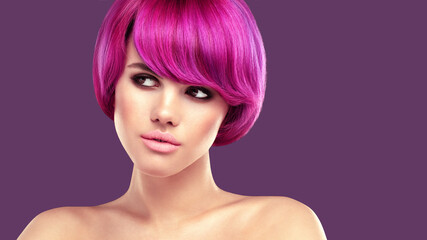Pink hair beauty portrait. Young beautiful woman with smokey eyes make up and colorful bob hairstyle is posing against purple background.
