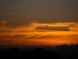 Cielo anaranjado al amanecer con avión