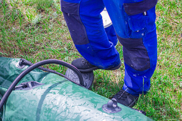 Fototapeta premium man inflating a rubber boat with a hand electric pump close-up, front and background blurred with bokeh effect