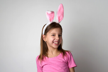 Obraz na płótnie Canvas Cute girl wearing bunny ears headband posing over white background