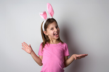 Cute girl wearing bunny ears headband posing over white background