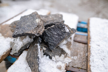 granite chips on snow covered wooden boards. Stone masonry, granite workshop. Leftovers from making stone sculpture.