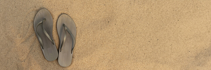 banner of light sandal or flip flops on the beach. golden sand. place for your text. top view....