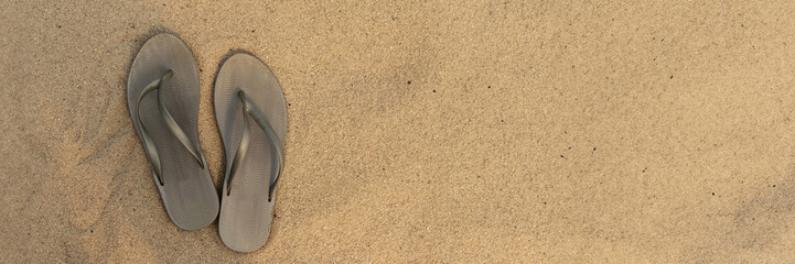 banner of light sandal or flip flops on the beach. golden sand. place for your text. top view. concept of summer and vacation at sea