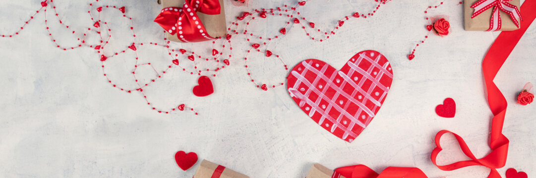 banner of heart from a red ribbon, gifts with a red ribbon and red hearts on a white stone background. Valentine's day background. Valentine's day concept. Flat lay.