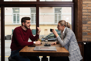 Young serious man having conversation with woman girlfriend sit at cafe table, focused male friend...