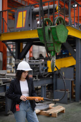 Latin woman engineer inspecting heavy machinery system in production line for manufacturing safety....