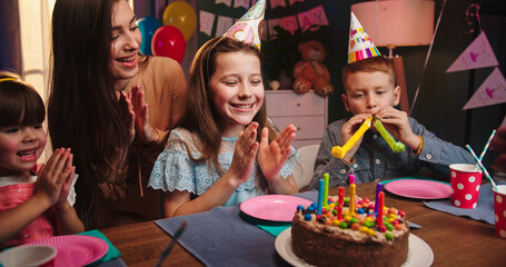 Pretty little Caucasian girl with her friends and mother sitting at the table and waiting for the...