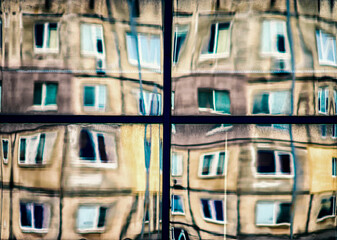 crooked reflection of houses in a glass window