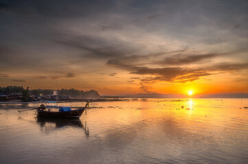 Morning sunrise with traditional long tail boats and fishing village background in southern Thailand