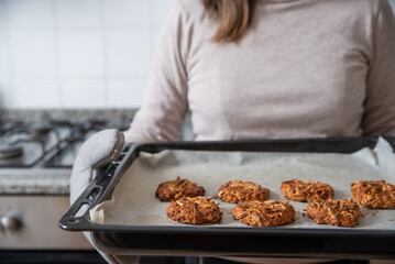 Woman holding baking tray with ready cookies.