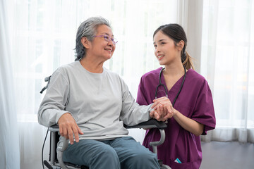 Asian young nurse taking care and talking mature female patient sitting on wheelchair in hospital. Healthcare concept.