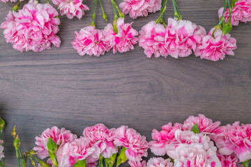 Obraz na płótnie Canvas 木のテーブルに置かれたピンクのカーネーション