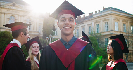 Portrait of the young happy handsome moulatto guy, master graduate student in the academic cap and...