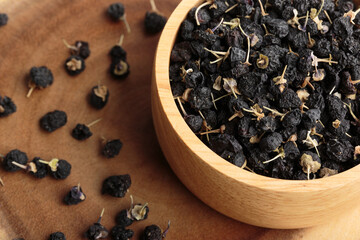 Black goji berry or black wolfberry in a wooden bowl.