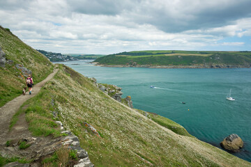 Hiker and dog approaching Salcombe from Bolt Head on the on the South West Coast Path, Devon, UK
