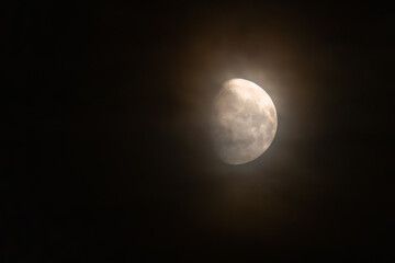 A bright moon in the night sky covered with a fine mist.