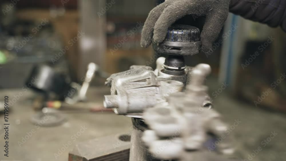 Poster A car mechanic unscrews the filter housing clamped in a mechanical vice. Replacing the filter