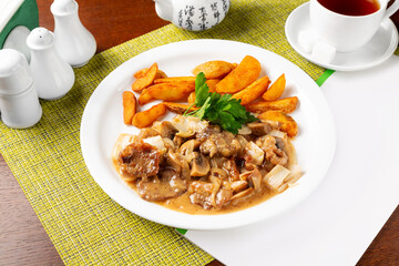 Pork pieces in cream sauce and fried potatoes.
