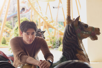 Close up face asian man smiling at Carousel in amusement park and turning head at front side.