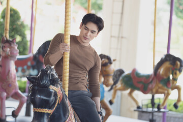 couple asian man and woman dating and riding on horse at Carousel amusement park. Concept happy and...