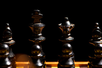 Chess pieces,beautiful old chess pieces on a board, black background, selective focus.