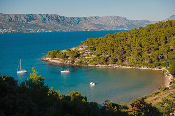 Top view of tranquil bay in Brac island with motor yachts and residential buildings. Green nature...