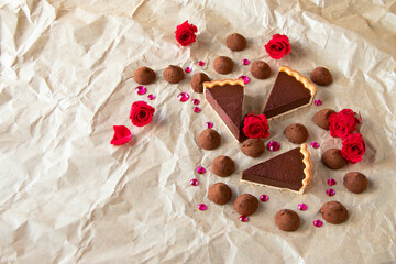 バレンタイン・イメージ　深紅のバラとピンクのストーンと自家製チョコレート・タルトとチョコレート菓子（しわくちゃのクラフト紙の背景）