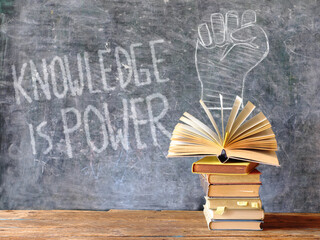 knowledge is power, books and blackboard with drawing of a fist  power...