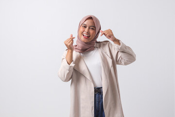 Portrait of excited Asian hijab woman in casual suit making korean heart sign means love to you. Showing sympathy and caring feelings. Isolated image on white background