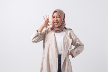 Portrait of excited Asian hijab woman in casual suit showing ok hand gesture and smiling looking at camera. Advertising concept. Isolated image on white background