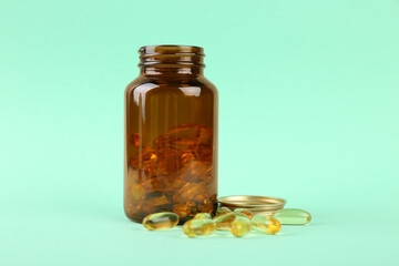 Jar with vitamin capsules on turquoise background