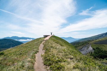 Silhouette of a person on the summit of a mountain with arms wide open.